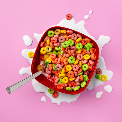 Bowl of colorful fruit loops with spilled milk around the bottom
