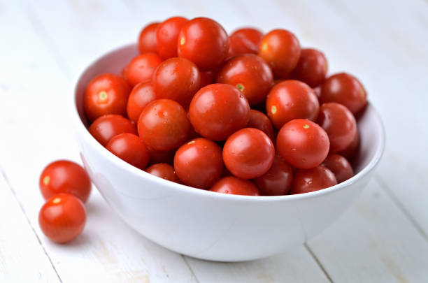 Bowl of fresh cherry tomatoes on rustic wooden background. stock photo