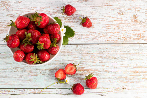 bowl of fresh strawberries on white wooden table with copy space. Top view stock photo