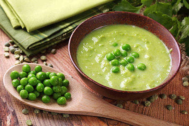 A bowl of green pea soup with a wooden spoon stock photo
