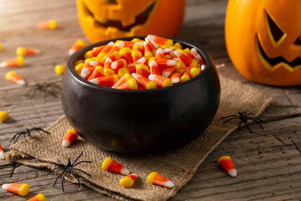 Bowl of Halloween Candy Corns and Jack O' Lantern Bowl of Halloween candy corns with jack o' lanterns and spider decoration on rustic wood table. candy stock pictures, royalty-free photos & images