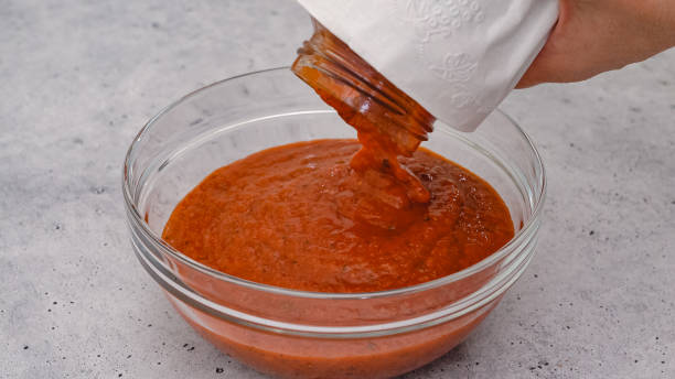 Bowl of marinara sauce close up on light grey background. Spinach lasagna step by step recipe stock photo