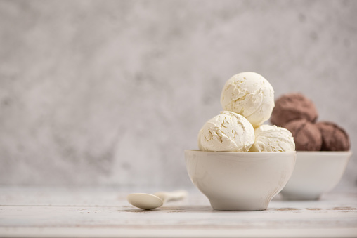 Bowl of vanilla and chocolate ice cream on light background. Side view. With copy space