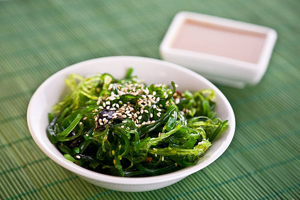 A bowl of Wakame seaweed salad Wakame seaweed salad with nut sauce, garnished with sesame seeds and red chili pepper seaweed stock pictures, royalty-free photos & images