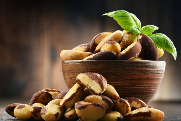 Bowl with Brazil nuts on wooden table stock photo