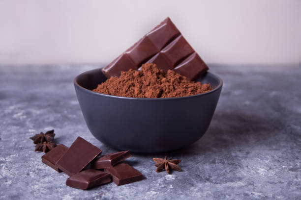 bowl with cocoa powder and pieces of chocolate on the gray background stock photo