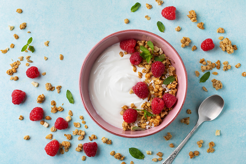 Bowl with greek yogurt, raspberries and granola. Top view flat lay. Healthy food and nutrition morning breakfast.