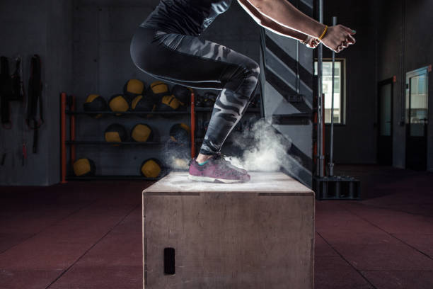 Box jump workout at gym gym closeup Young woman jumping box and talc powder departs from under feet. Fitness woman doing box jump workout at gym gym. cross training stock pictures, royalty-free photos & images