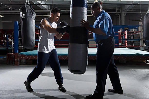 Boxer and coach with heavy bag  boxing trainer stock pictures, royalty-free photos & images