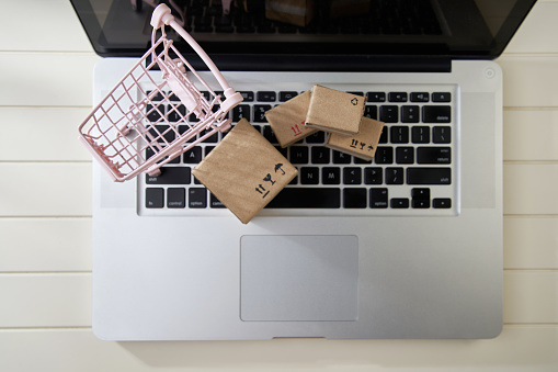 Online shopping and delivery service concept. Paper cartons in a shopping cart on a laptop keyboard,