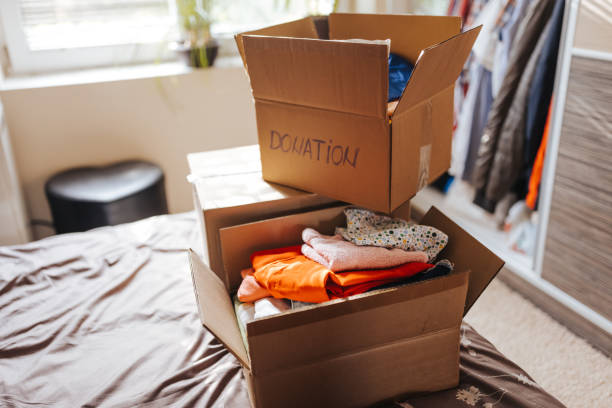 dozen met kleren voor schenking in huisbinnenland - kleding stockfoto's en -beelden