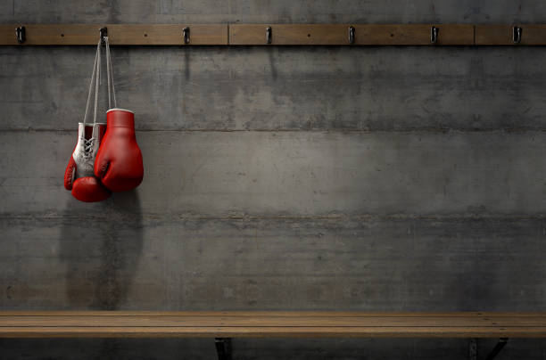 Boxing Gloves Hanging In Change Room Spotlit boxing gloves hanging on a hanger above an empty wooden bench in a locker change room - 3D render boxing gloves stock pictures, royalty-free photos & images