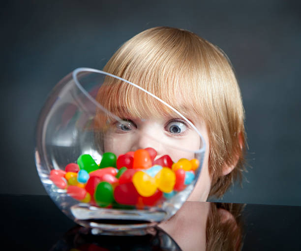 Boy And Candy Little boy with big blue eyes looks at a candy jar. candy jar stock pictures, royalty-free photos & images