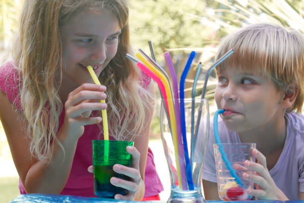 Boy and girl drinking with alternative (non-plastic) straws stock photo