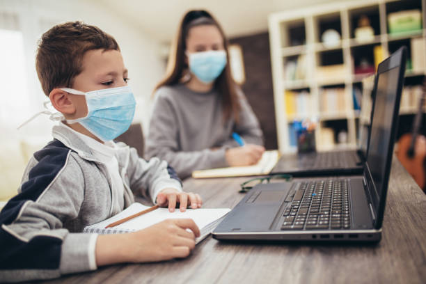 boy and girl studies at home, wear protective masks, and doing school homework. distance learning online education.online education. - teacher back to school imagens e fotografias de stock