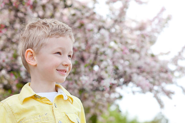 cheerful smiling boy looking forward with beautiful blooming apple...