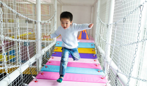 Boy crossing the bridge on a playground Boy crossing the bridge on a playground. indoor playground stock pictures, royalty-free photos & images