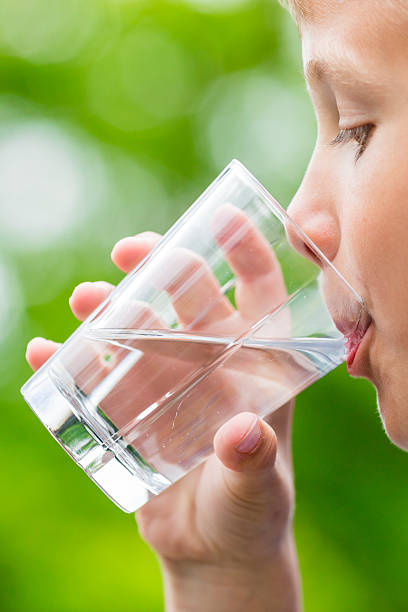 Boy drinking fresh water from glass stock photo
