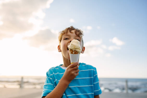 Boy eating an ice cream Boy eating an ice cream standing near seafront. Little boy on vacation treating himself to an ice cream. ice cream stock pictures, royalty-free photos & images