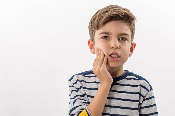 boy having a toothache holding his face with his hand - abces stockfoto's en -beelden