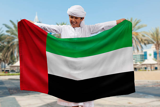 Boy Holding Flag Arabian Boy Holding UAE Flag Outdoors united arab emirates flag stock pictures, royalty-free photos & images