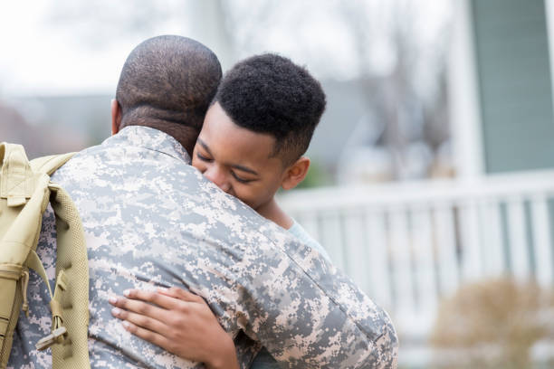 Boy is reunited with military dad African American preteen boy hugs his father as his father returns home from overseas assignment. soldiers returning home stock pictures, royalty-free photos & images