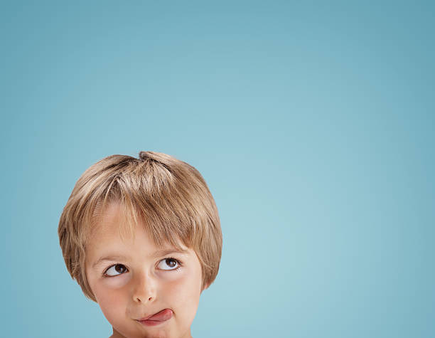 Boy looking up with tongue out licking his lips Boy with tongue out licking his lips looking up at copy space for a message or product placement hungry stock pictures, royalty-free photos & images
