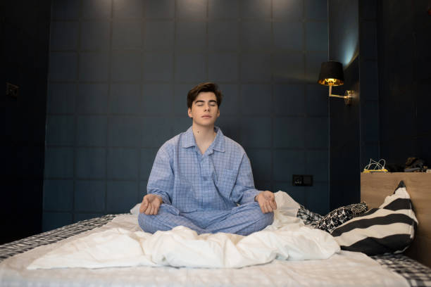 jongen mediteren op bed - alleen één tienerjongen stockfoto's en -beelden