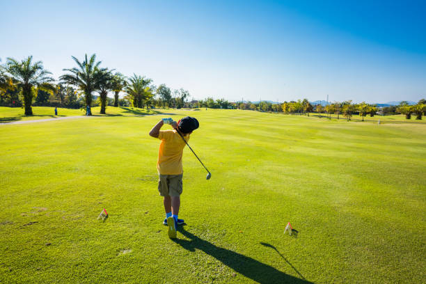 boy play golf in green course stock photo
