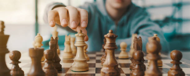 Boy playing chess and moving a piece stock photo