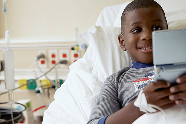Boy playing video games in a hospital  Portable DVD Player stock pictures, royalty-free photos & images