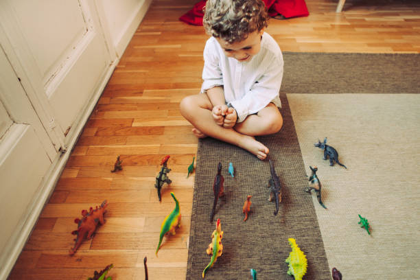 Chłopiec bawi się dinozaurami z kamiłę jak i kąskiem
