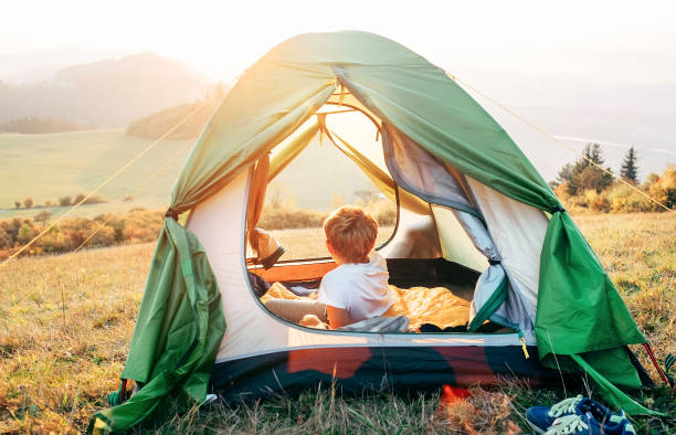 Boy rest in camping tent and enjoy with sunset light in mountain valley Boy rest in camping tent and enjoy with sunset light in mountain valley scout camp stock pictures, royalty-free photos & images