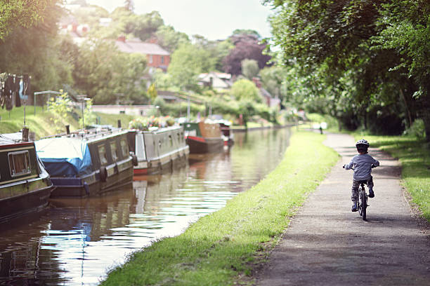 Boy riding his bike Riding a bicycle on a tow path by a canal concept for healthy lifestyle, exercising and vacations canal stock pictures, royalty-free photos & images