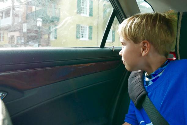 Boy riding in a car, looking out the window stock photo