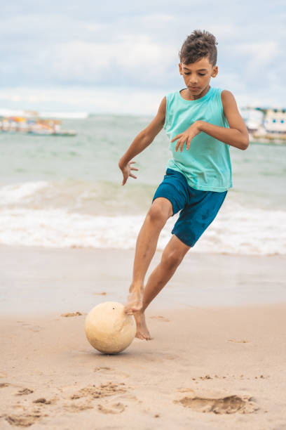 boy running his foot over the ball - futebol de praia imagens e fotografias de stock