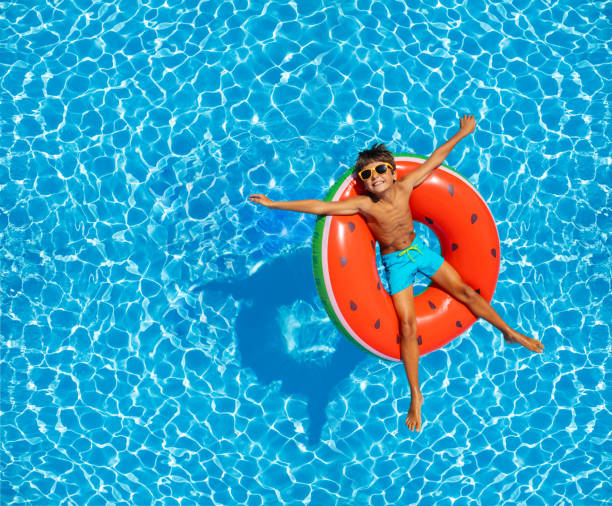 Boy swim in pool on inflatable ring from above stock photo