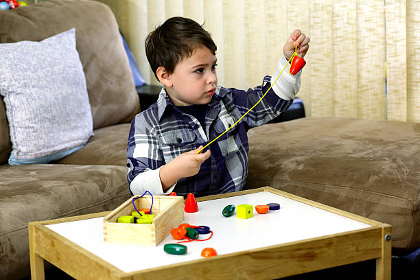 Boy threading a string of beads stock photo