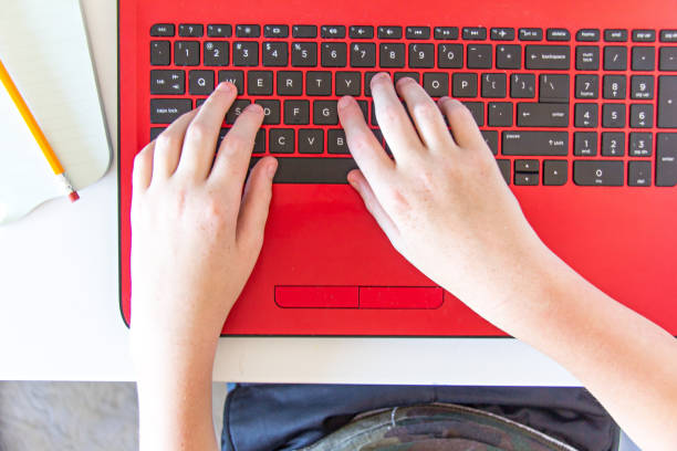 Boy typing on red laptop stock photo
