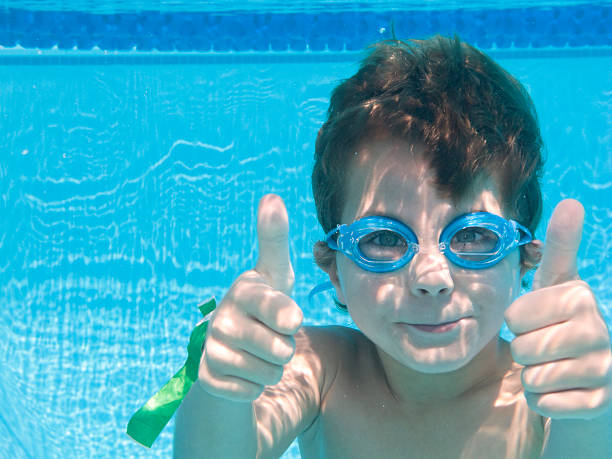 Boy Underwater In Swimming Pool With Thumbs Up. stock photo