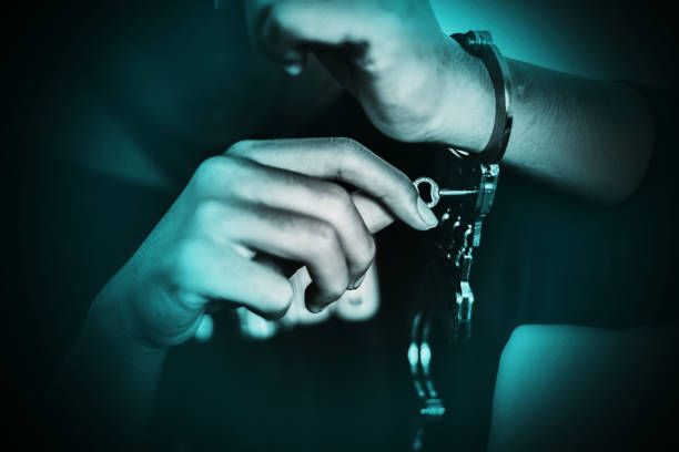 Boy unlocking handcuffs that bind him, escape from the arrest concept stock photo