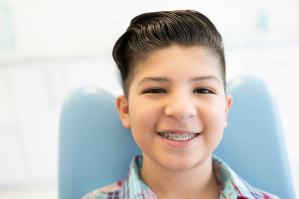 Boy Visiting Orthodontic Center Closeup portrait of smiling cute Latin boy wearing braces in a dental clinic dental braces stock pictures, royalty-free photos & images
