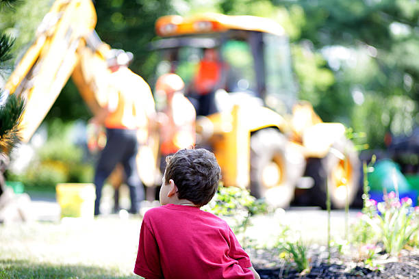 Boy with autism watches the construction work in the street stock photo