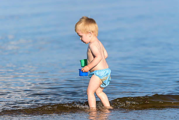 Boy with hearing aid playing in water stock photo