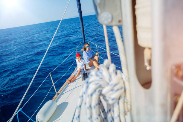 Boy with his mother on board of sailing yacht on summer cruise. stock photo
