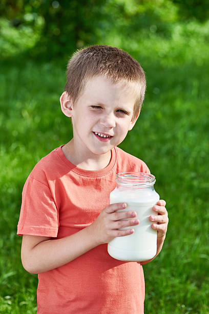 Happy boy with jug of milk in sunny garden