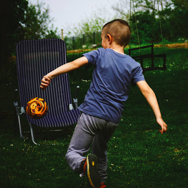 Boy With Mohawk Haircut Kicking A Ball Stock Photo Download