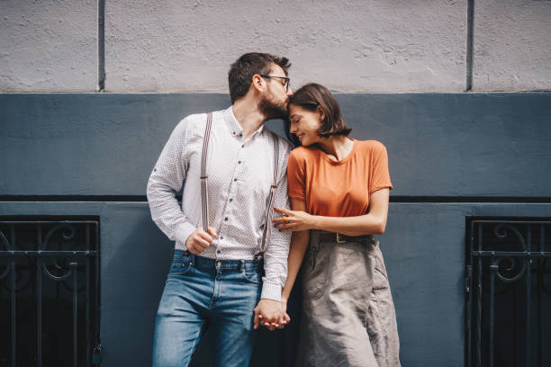Boyfriend kissing his girlfriend by the wall. stock photo