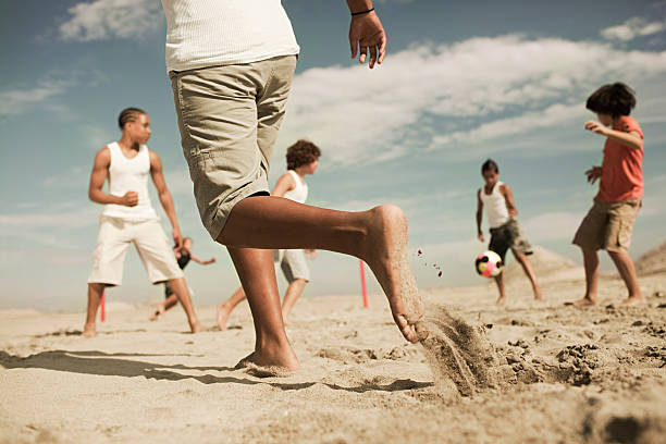 boys playing football on beach - voeten in het zand stockfoto's en -beelden