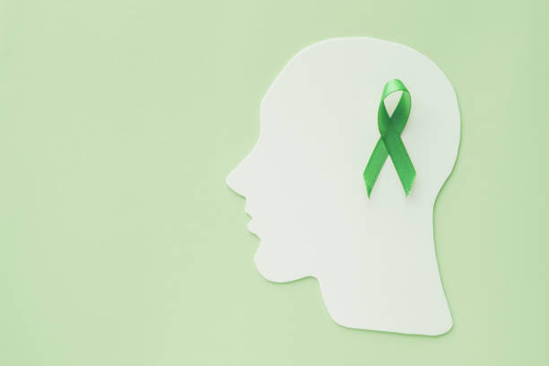 brain paper cutout with green ribbon on green background,  mental health concept, world mental health day brain paper cutout with green ribbon on green background,  mental health concept, world mental health day mental health awareness stock pictures, royalty-free photos & images